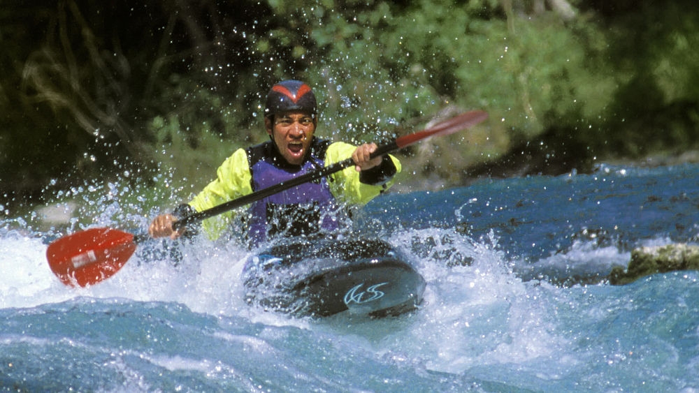 Um homem anda rapidamente em uma canoa com um remo em um rio