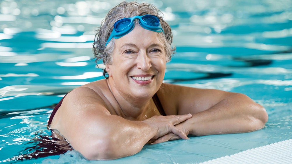 mulher na piscina usando óculos de natação na testa