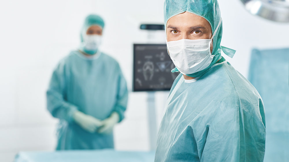 Dois cirurgiões com o OrthoPilot® Elite ao fundo