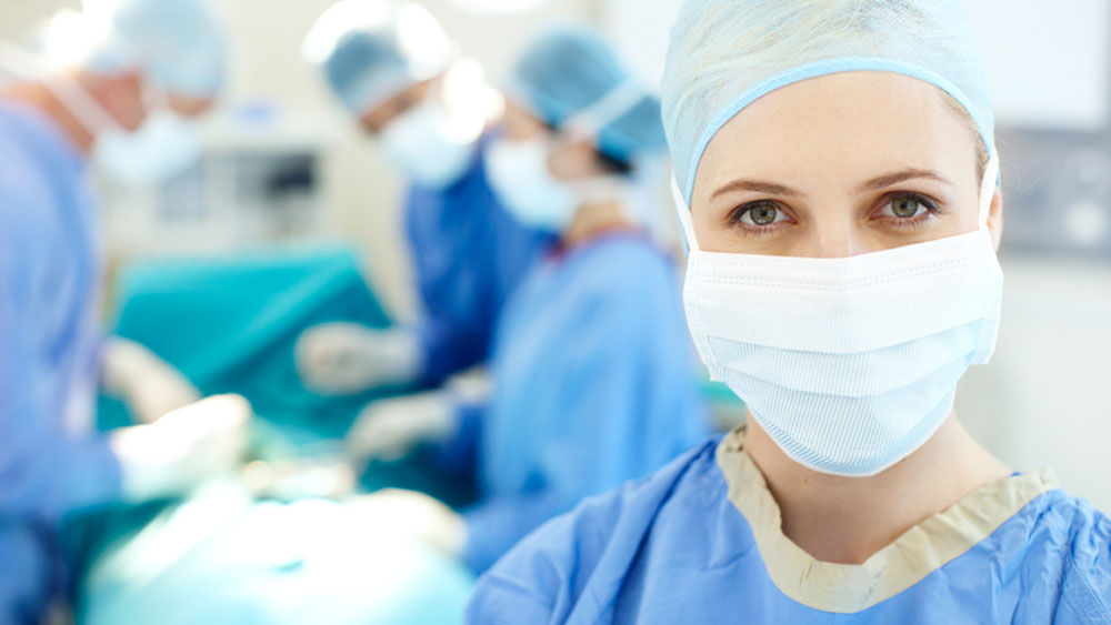 Em primeiro plano, uma cirurgiã e, ao fundo, três outros cirurgiões durante uma operação