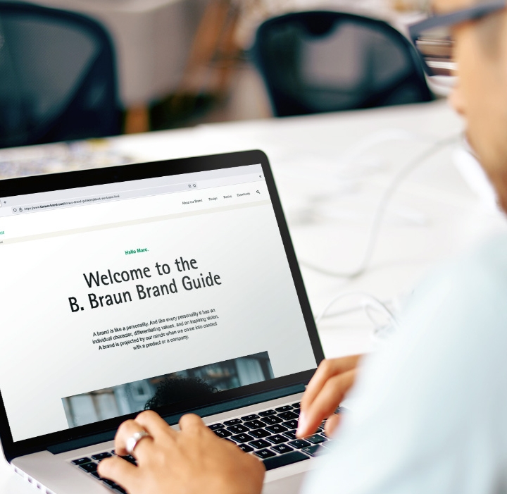 Um homem de camisa azul clara operando um laptop com o site da B. Braun aberto.