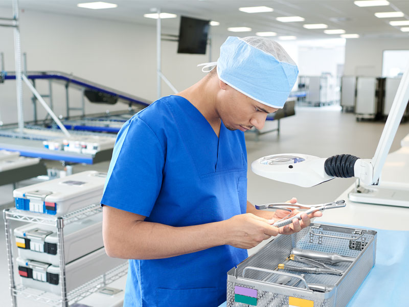 Um profissional de saúde está inspecionando instrumentos cirúrgicos em sistemas de recipientes esterilizados