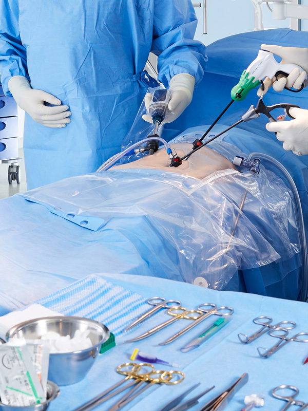 Dois profissionais de saúde realizando cirurgia laparoscópica com instrumentos finamente curvados, com foco em precisão e técnicas minimamente invasivas