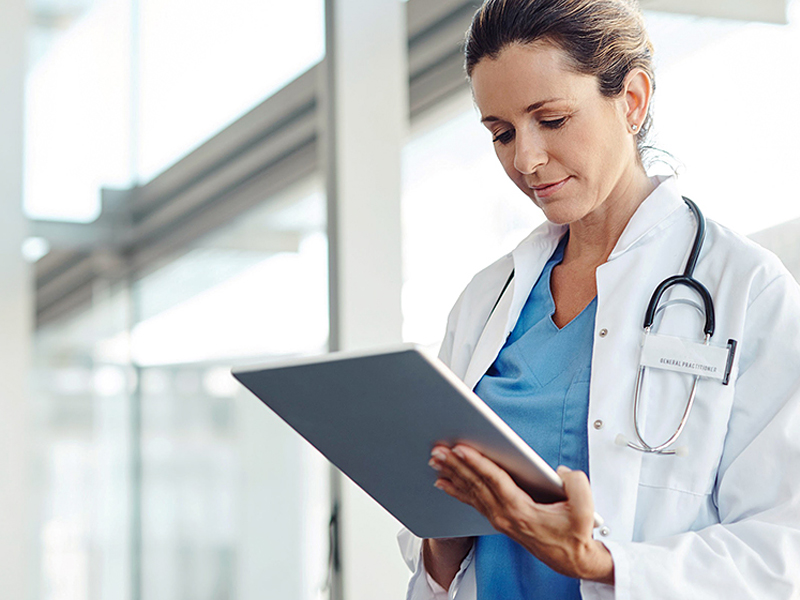 Uma médica olha para um tablet em suas mãos