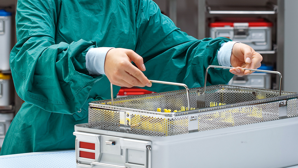 O funcionário do CSSD levanta uma cesta com instrumentos de um recipiente esterilizado