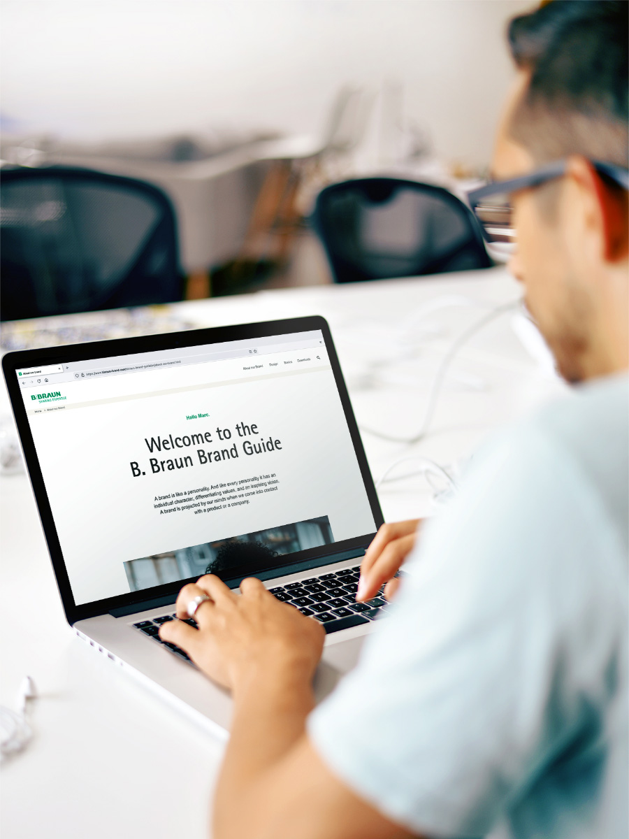 Um homem de camisa azul clara operando um laptop com o site da B. Braun aberto.
